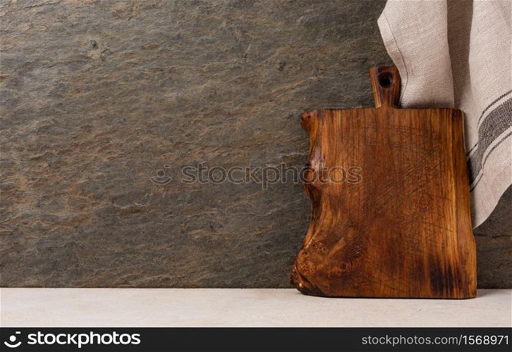 Rustic wooden cutting board on rusty stone background. Cutting board on wooden kitchen table