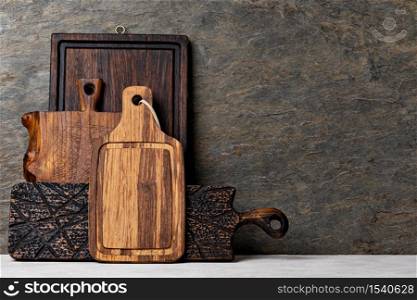 Rustic wooden cutting board on rusty stone background. empty copy space for text, design element. Cutting board on wooden kitchen table