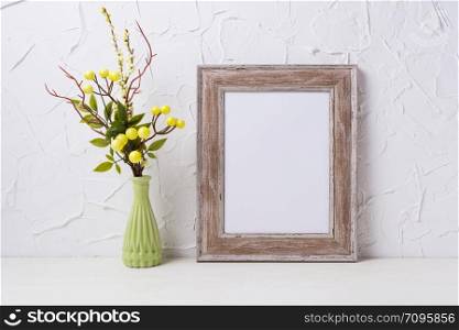 Rustic wooden frame mockup with yellow decorated branches in the green vase. Empty frame mock up for presentation design. Template framing for modern art.