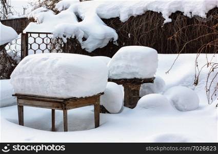 Rustic wooden tables and bench in the yard under a thick layer of snow after a snowfall on a winter day. Russia. Selective focus.. Rustic Yard After A Snowfall