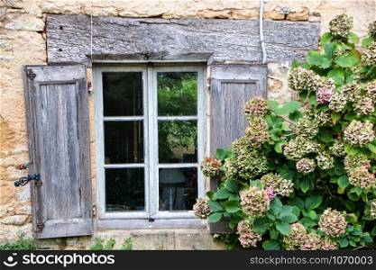 rustic wooden window on a stone wall at saint amand de coly , perigord noir in aquitaine, france