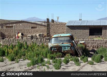 Rusty car in the garden of village, Bolivia