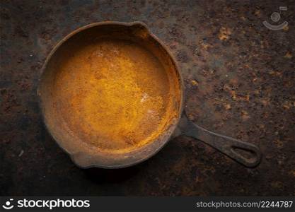 rusty cast iron skillet on a dirty rust metal plate texture background, top view