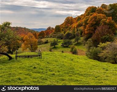 Rusty farm hay tedder implement by hills of autumn colors in Vermont. Horse drawn rake by fall colors in Vermont