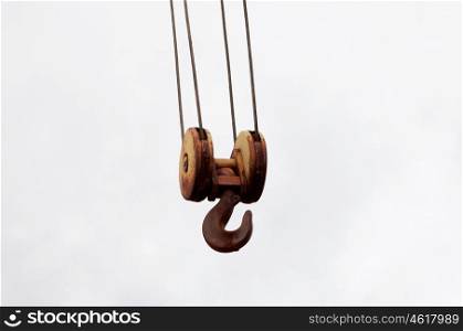 Rusty hook of a crane on a gray sky