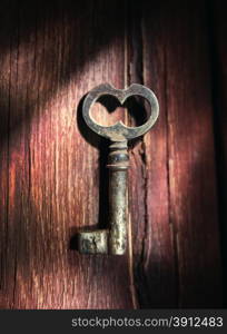 Rusty key on old wooden surface