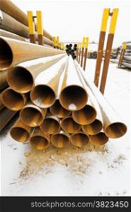 rusty steel pipes in stacks on outdoor warehouse in winter