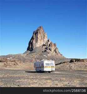 RV travelling toward rock formation in the desert of Monument Valley, Utah.