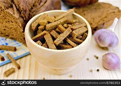 Rye homemade bread, croutons in a wooden bowl, garlic, pepper peas, blue cloth on a background of wooden boards