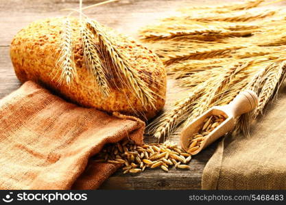 Rye spikelets and bread on wooden background