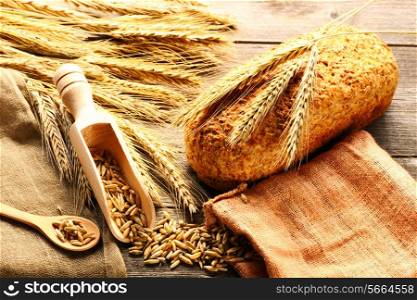 Rye spikelets and bread on wooden background