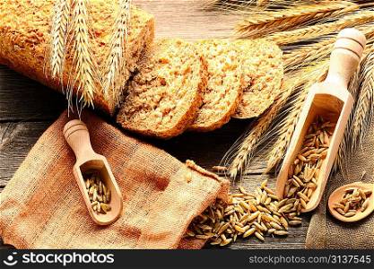 Rye spikelets and sliced bread on wooden background