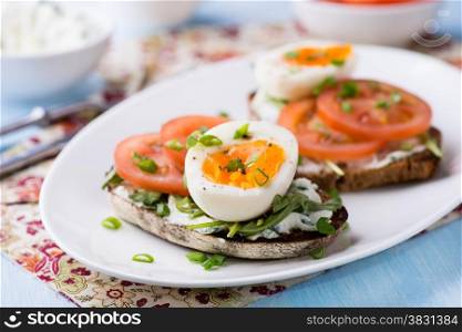 Rye toast sandwiches with egg, tomato and soft cheese, selective focus