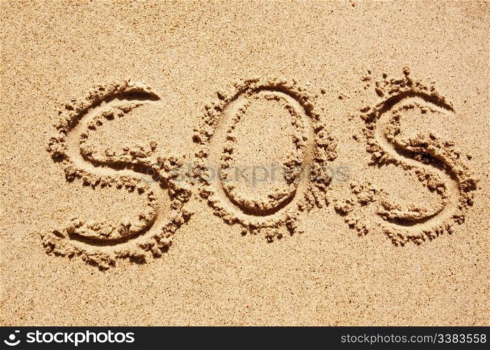 S.O.S written in the sand with a finger or stick
