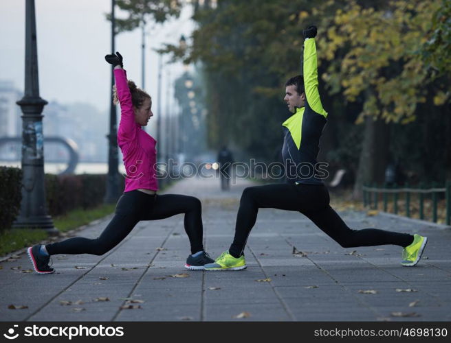 s young jogging couple warming up and stretching before morning running in the city