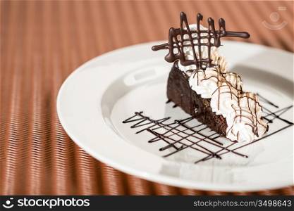 Sacher cake with whipped cream on chocolate background