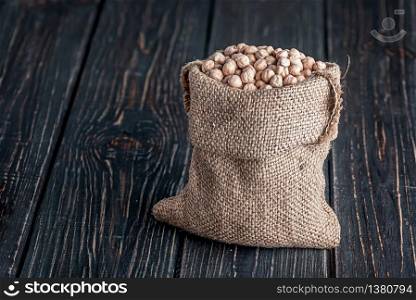 Sack of chickpeas stands on wooden background. Sack of chickpeas stands on desk