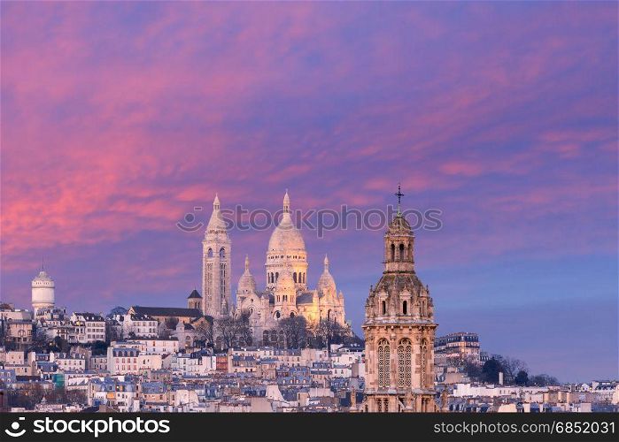 Sacre-Coeur Basilica at sunset in Paris, France. Aerial view of Sacre-Coeur Basilica or Basilica of the Sacred Heart of Jesus at the butte Montmartre and Saint Trinity church at nice sunset, Paris, France