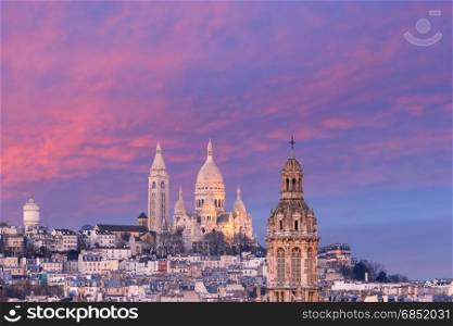 Sacre-Coeur Basilica at sunset in Paris, France. Aerial view of Sacre-Coeur Basilica or Basilica of the Sacred Heart of Jesus at the butte Montmartre and Saint Trinity church at nice sunset, Paris, France