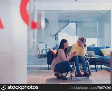 Sad and depressed disabled businesswoman in a wheelchair at the office getting support and assistance of female coworker friend. Modern open space office or hospital. Sad and depressed disabled businesswoman in a wheelchair at the office getting support and assistance of female coworker friend