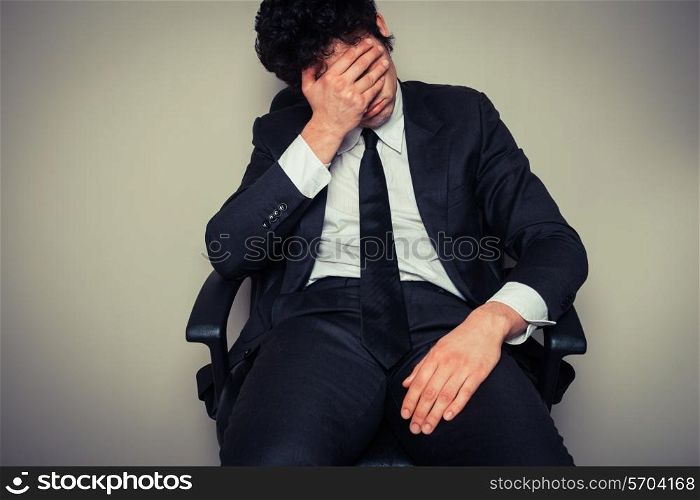Sad and tired young businesman sitting in an office chair