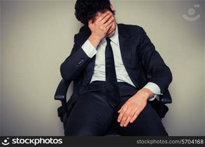 Sad and tired young businesman sitting in an office chair