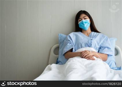 Sad Asian patient woman lying on the hospital bed and wearing a face mask to protect coronavirus. Concept of Health care, quarantine coronavirus (COVID-19), and Health insurance.
