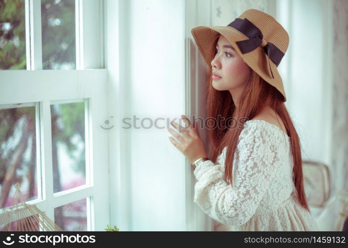 Sad asian vintage woman on the window looking out the window