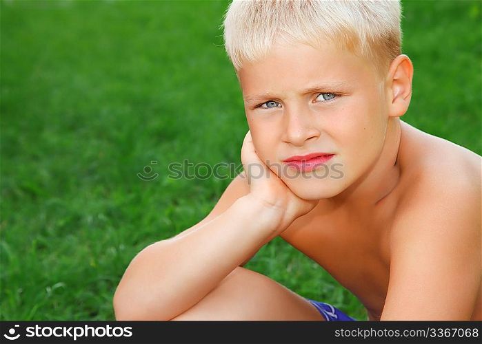 sad boy sitting on meadow