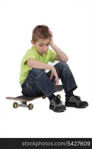 Sad boy sitting on skateboard