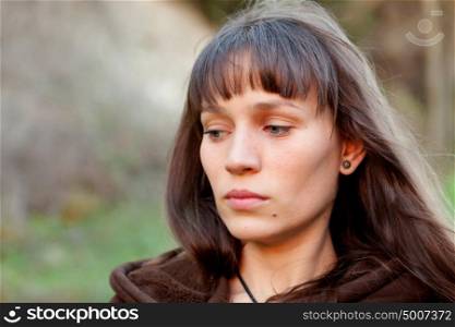 Sad brunette woman with blue eyes in the park
