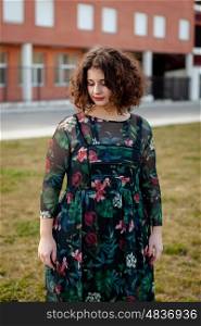 Sad curvy girl with curly hair in the street with a flowered dress