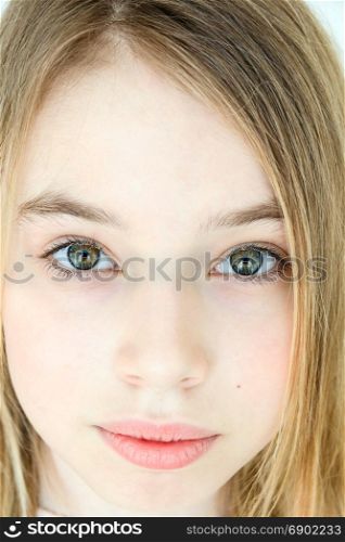 Sad cute girl eleven years old with blond long hair and green eyes