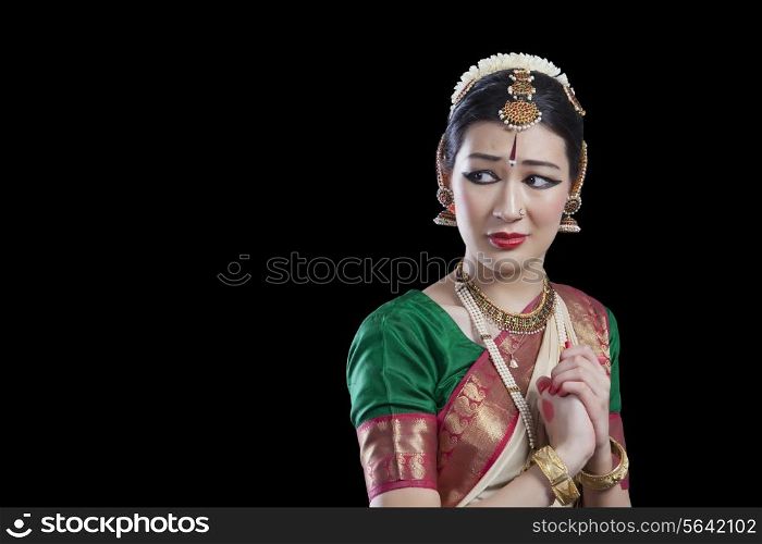 Sad dancer performing Bharatanatyam over black background