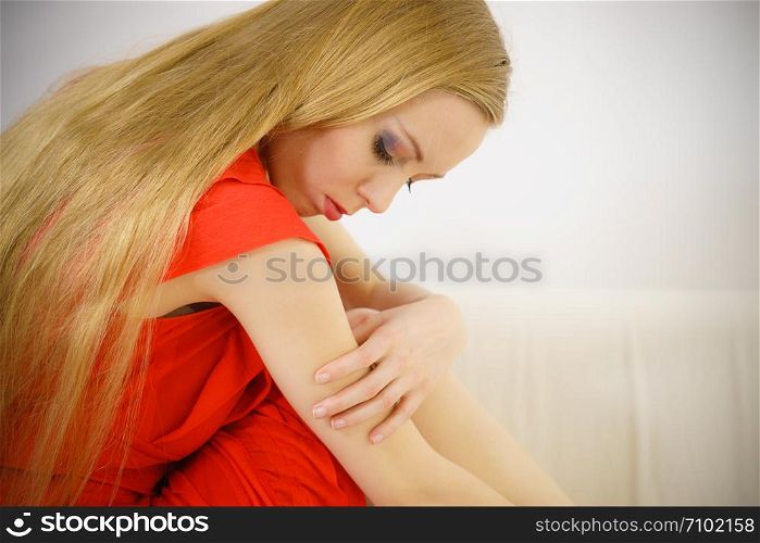 Sad elegant woman with long hair sitting on sofa being depressed, tired, exhausted having bad mood.. Sad elegant woman sitting on sofa