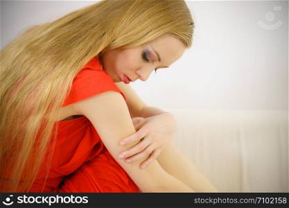 Sad elegant woman with long hair sitting on sofa being depressed, tired, exhausted having bad mood.. Sad elegant woman sitting on sofa