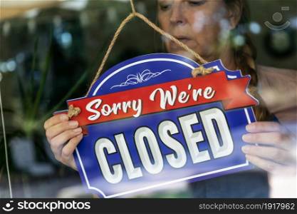 Sad Female Store Owner Turning Sign to Closed in Window.