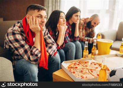 Sad friends watching TV at the boring house party. Bad friendship, group of bored people leisures together