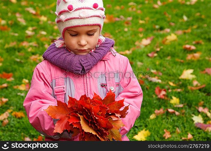Sad girl in autumn park with a bunch of leaves