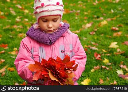 Sad girl in autumn park with a bunch of leaves