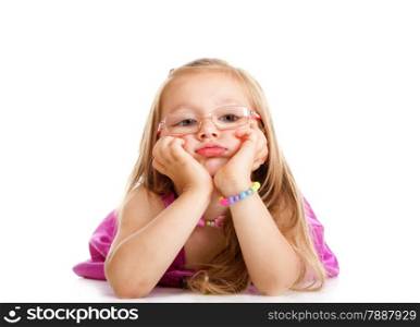 Sad little girl in glasses laying on floor leaning on elbows, chin in hands, looking isolated over white