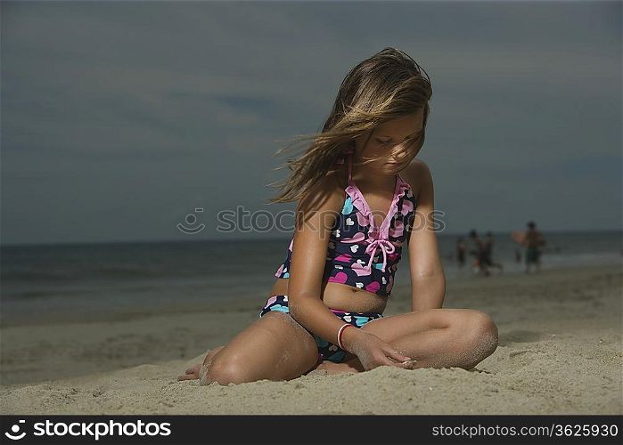 Sad Little Girl Sitting on a Beach