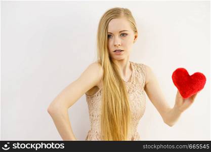 Sad lonely woman being alone holding red heart shape. Female missing someone during valentines.. Sad woman on Valentines day