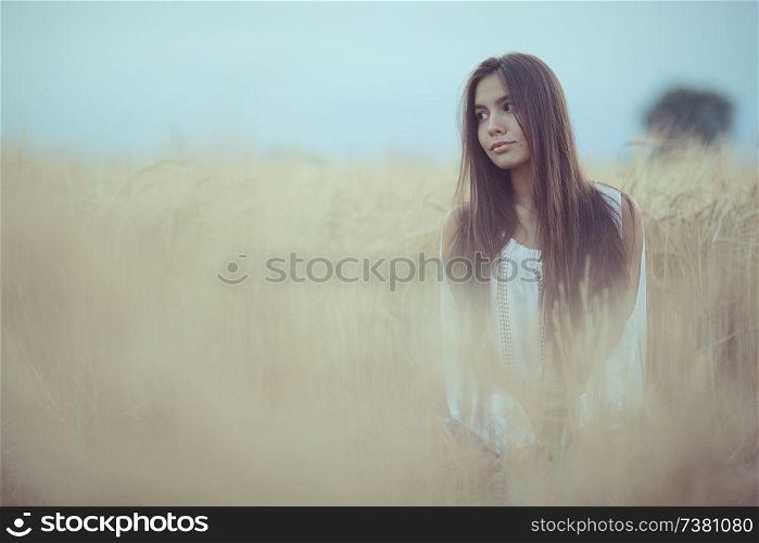 Sad lonely young girl in a field bored with depression