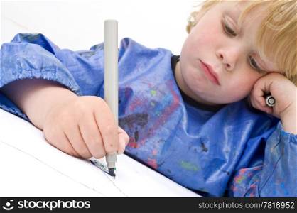 Sad looking child making a drawing with a felt-pen. Focus on the felt tip pan and hand