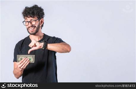 Sad man holding banknote, Sad man with a banknote with thumb down, concept of man with little money