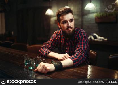 Sad man sitting at the bar counter, alcohol addiction. Male person in pub, alcoholism. Sad man sitting at bar counter, alcohol addiction
