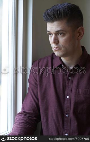 Sad Man Suffering From Depression Looking Out Of Window