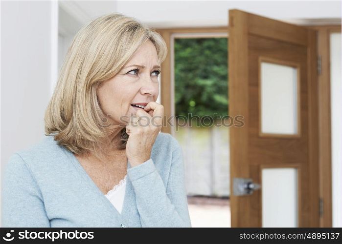 Sad Mature Woman Suffering From Agoraphobia Looking Out Of Open Door