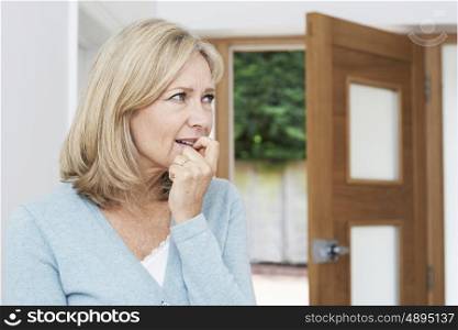 Sad Mature Woman Suffering From Agoraphobia Looking Out Of Open Door